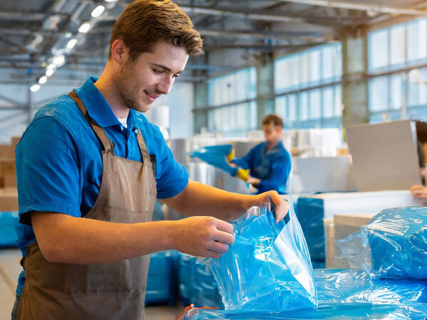 Mitarbeiter einer Firma packen Metallgegenstände in VCI-Folie ein