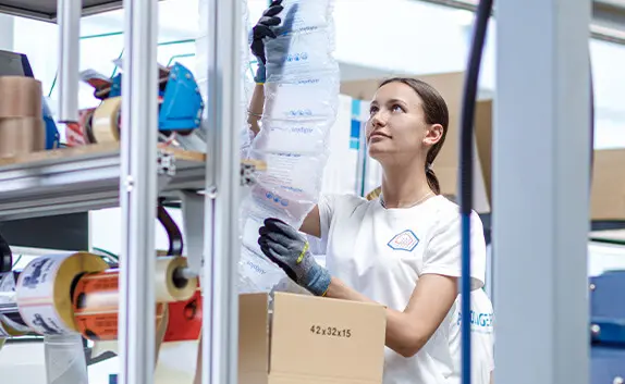 Eine Logistikmitarbeiterin sichert Produkte mit Luftpolster.