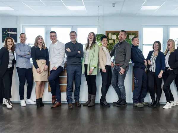 Team von PRODINGER Mitarbeitern lächelt in die Kamera.