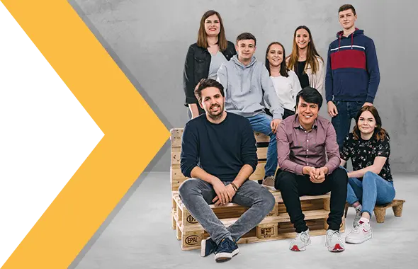 Mehrere Auszubildende von PRODINGER sitzen auf Holzpaletten