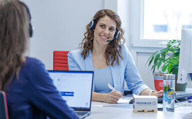 Eine Mitarbeiterin der PRODINGER Verpackung arbeitet an einem modernen PC-Arbeitsplatz gemeinsam mit ihren Team-Kollegen.