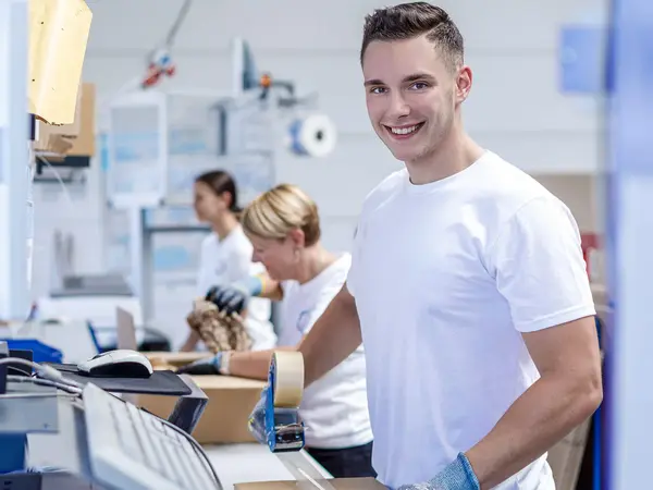 Ein Logistikmitarbeiter verschließt ein Paket mit Klebeband.