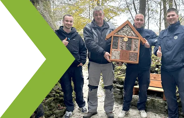 Das Bild 3 Logistik-Mitarbeiter von PRODINGER Verpackung, die ein Insektenhotels beim PRODINGER Hands-On Aktionstag übergeben bekommen.